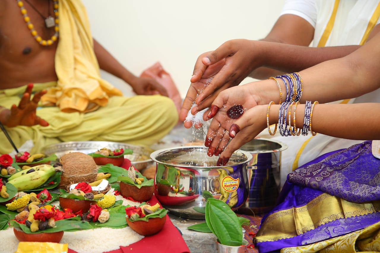 Hands performing a traditional Indian ritual ceremony with offerings and cultural attire.